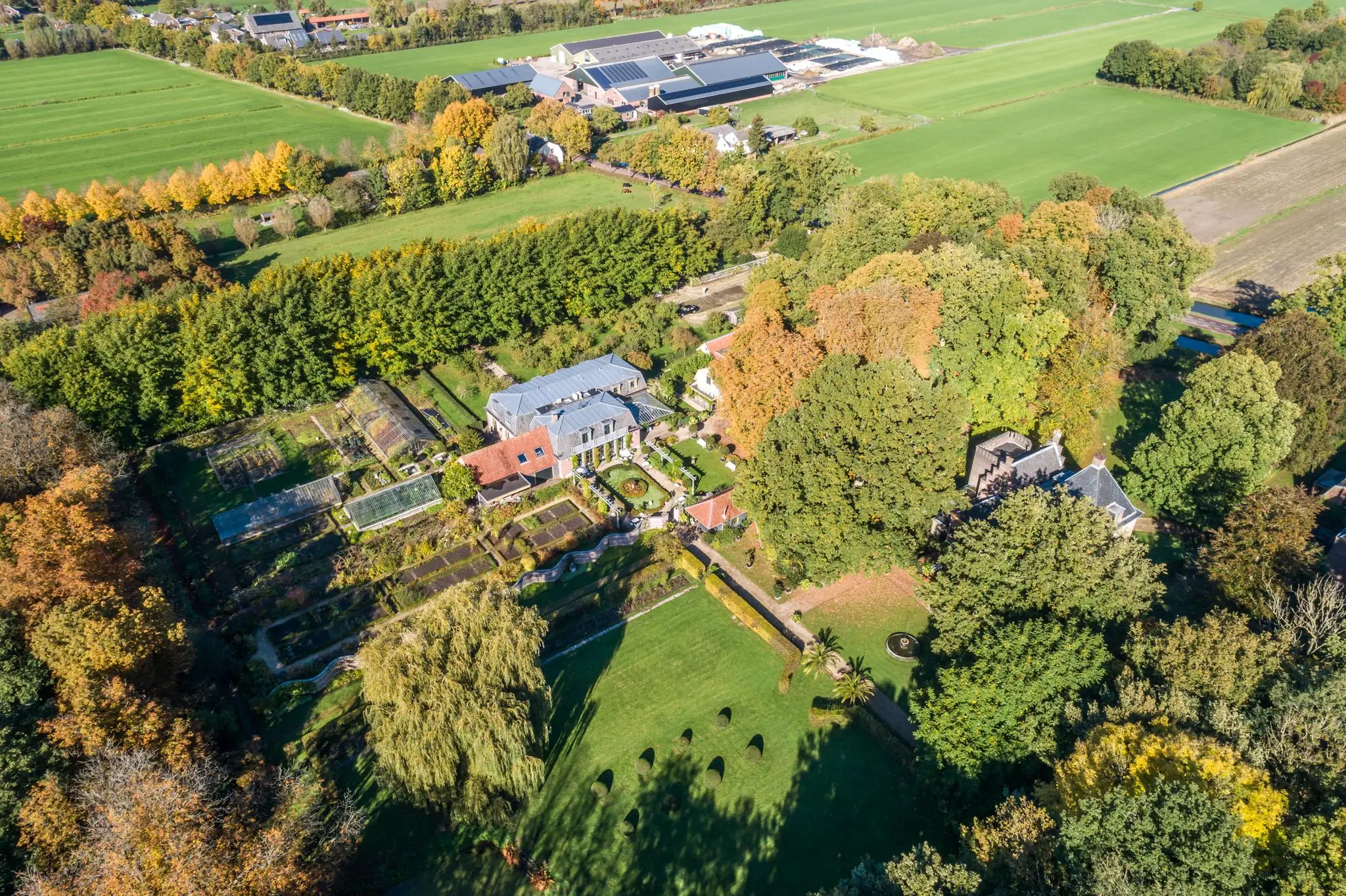 Luchtfoto van een landgoed met moestuin en siertuin aan de Langbroekerdijk A, omringd door groen en landbouwvelden.